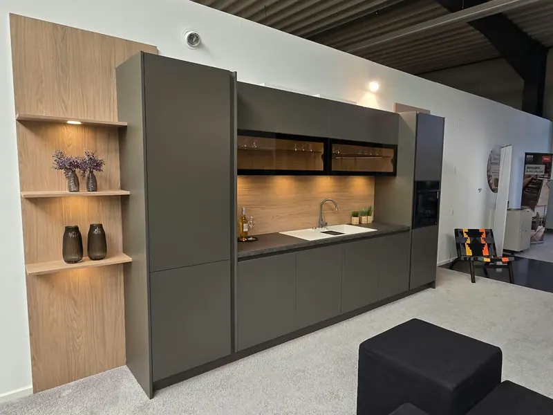 Keukenwand met donkere fronten, een houten achterwand en een verlichte houten nis