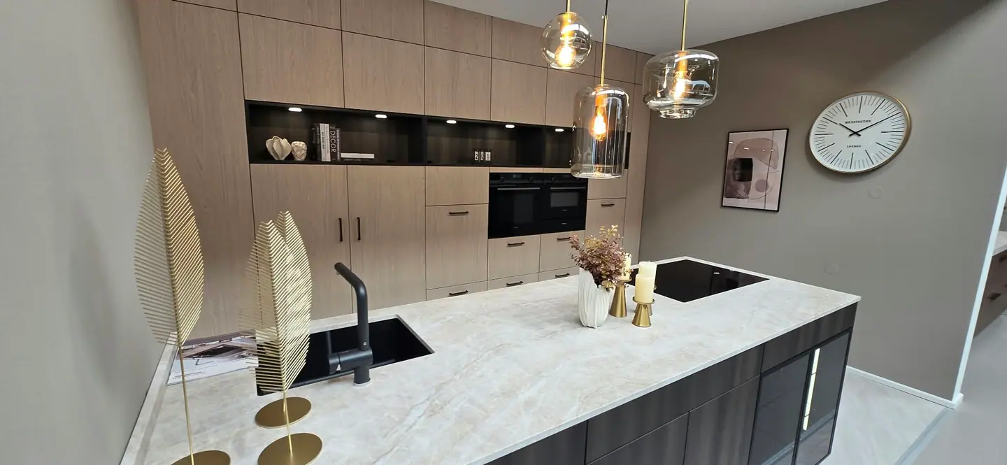 Keuken met lichte houten kasten, open nissen en een kookeiland met licht werkblad